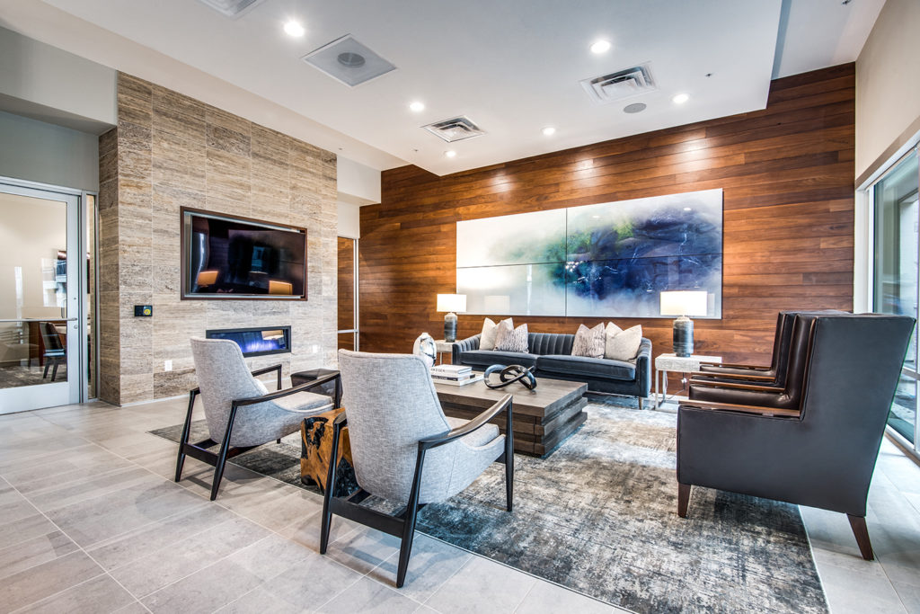 Clubroom lounge with comfortable armchairs and sofa, coffee table, fire place, and large TV