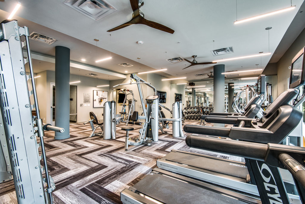 Fitness gym with ceiling fans, treadmills, and strength training equipment