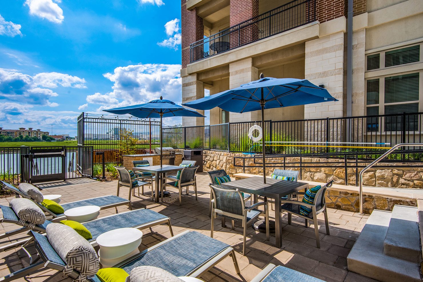 Outdoor lounge area with umbrella tables, chairs, and loungers with view of Lake Carolyn