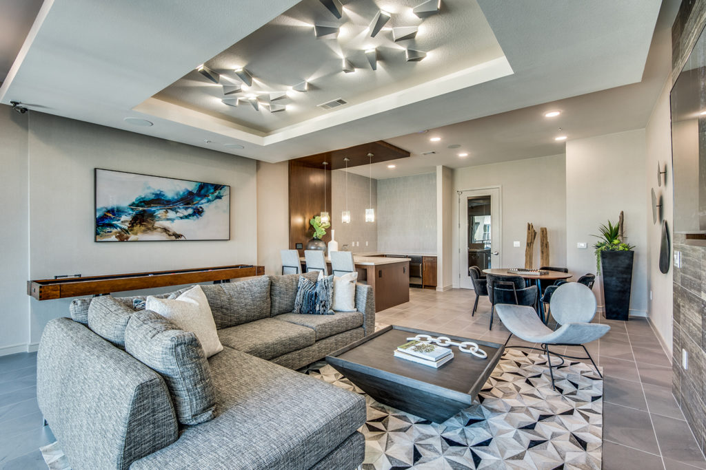Community clubroom with large sofa, shuffleboard, gaming tables, and TV