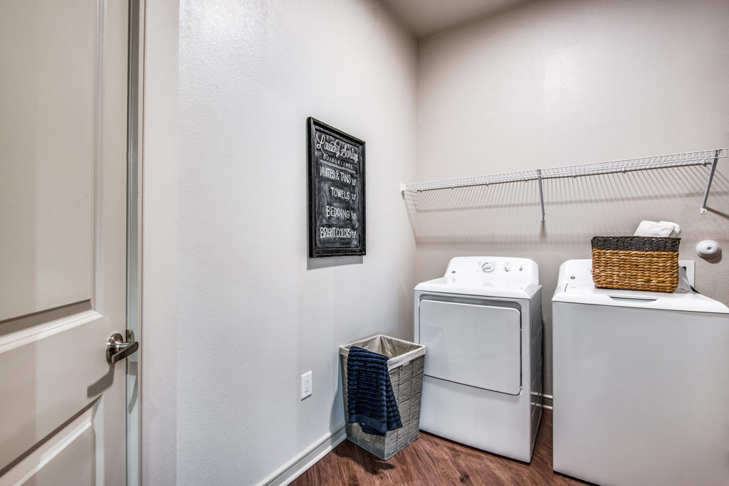 In-home laundry room with built-in shelving, washer, and dryer machine with wood-style flooring